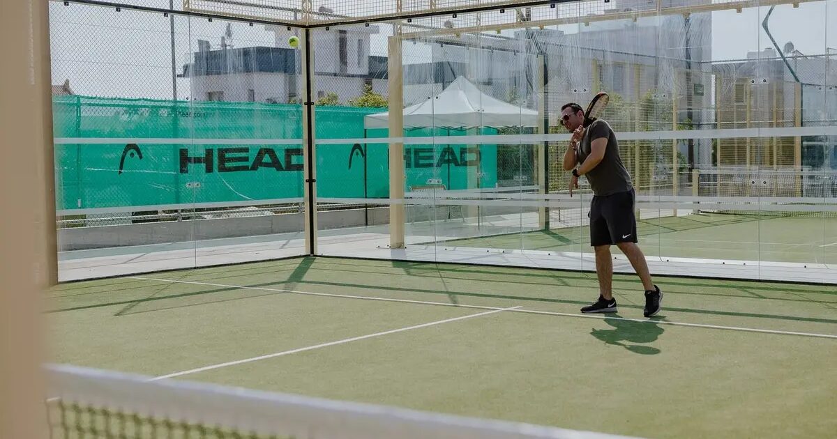 Padel court with glass walls and player in action, Cyprus